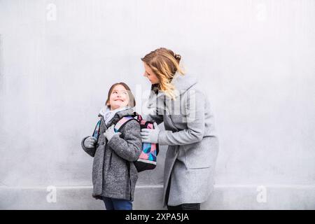 Mère emmenant sa fille à l'école, disant au revoir devant le bâtiment de l'école, se dirigeant vers le travail. Concept d'équilibre entre vie professionnelle et vie privée pour les femmes. Banque D'Images