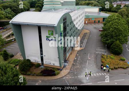 NOTE DE LA RÉDACTION : LANGUE DANS GRAFFITTI SUR LE MUR Une vue par drone de la police à l'Holiday Inn Express à Tamworth, Staffordshire, après qu'une foule l'a attaquée dimanche dans ce que la police a déclaré être des «actes violents de brutalités». Un grand groupe d'individus a été vu dans la région de la ville de Staffordshire, avec des gens qui ont lancé des projectiles, brisé des fenêtres, déclenché des incendies et ciblé la police. Date de la photo : lundi 5 août 2024. Banque D'Images