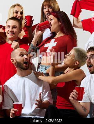 Groupe de jeunes, hommes et femmes s'habille dans les couleurs du drapeau du pays, soutenant l'équipe préférée pendant le match de football Banque D'Images