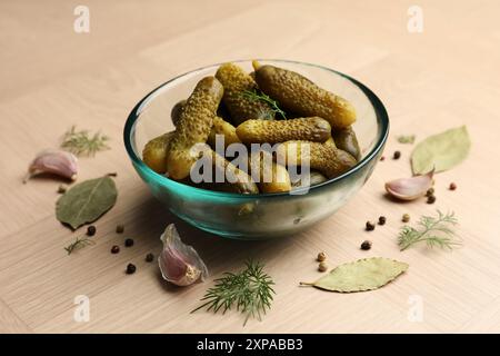 Concombres marinés dans un bol et épices sur une table en bois clair Banque D'Images
