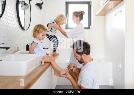 Routine de salle de bain du matin pour les petits enfants. Père peignant les ongles des filles, s'amusant. Banque D'Images