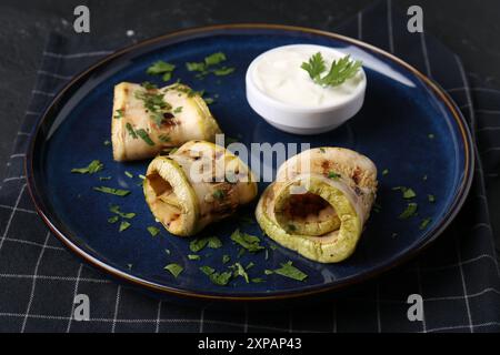 Savoureuses tranches de courgettes grillées servies avec sauce sur table Banque D'Images