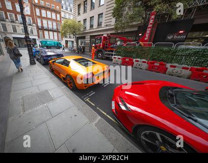 Stratton Street, Mayfair, Londres, Royaume-Uni. 5 août 2024. Une ligne de six voitures de sport de luxe (Ferrari, Lamborghini, Porsche) sont garées à l'extérieur du Mayfair, chacune récupérant apparemment des tickets de stationnement au fur et à mesure que la matinée se prolonge. Crédit : Malcolm Park/Alamy Live News Banque D'Images