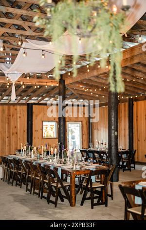 Réception de mariage intérieure rustique avec tables en bois et jeux de lumières Banque D'Images