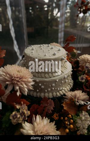 Gâteau de mariage décoré de perles entouré de fleurs d'automne Banque D'Images