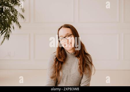 Jeune femme hispanique souriante en pull gris, cadre intérieur propre Banque D'Images