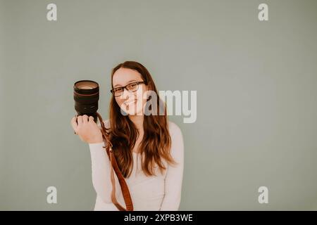 Photographe hispanique souriante tenant un appareil photo Banque D'Images