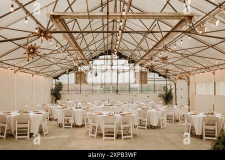 Réception de mariage dans une serre avec guirlande lumineuse et tables Banque D'Images