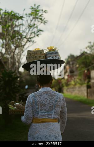 Une femme porte des offrandes aux esprits sur sa tête, Bali. Banque D'Images