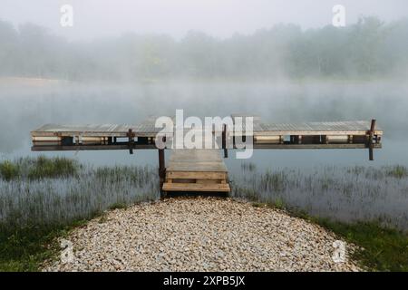 Brouillard suspendu au-dessus du quai en bois sur le bord du lac tôt le matin Banque D'Images