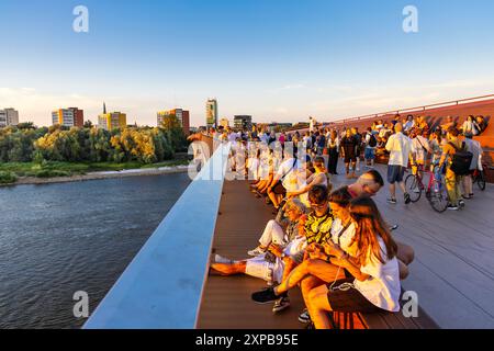 Les gens regardant le coucher du soleil depuis le pont piétonnier et cycliste le plus récent, reliant la vieille ville à Praga, Varsovie, Pologne Banque D'Images