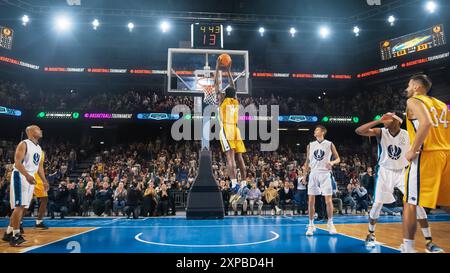 Afro-américain National Basketball Superstar joueur obtenant un puissant objectif Slam Dunk avec les deux mains devant le public de fans Cheering. Sports cinématographiques filmés avec vue arrière. Banque D'Images