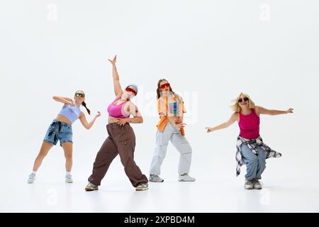 Filles dansant, streetwear habillé, avec une expression amusante et énergique sur fond blanc de studio. Fusion de la danse moderne avec des poses audacieuses Banque D'Images