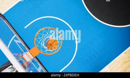 Vue descendante d'un ballon de basket-ball passant par un cerceau sur le terrain de sport de l'International Arena. Terrain de jeu vide où les matchs professionnels et les jeux ont lieu en attente du début du tournoi. Banque D'Images