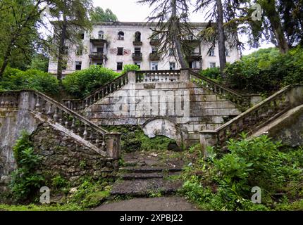 Bâtiment abandonné dans la ville d'Akarmara, ville de Tkvarcheli, Abkhazie. Ancienne architecture urbaine envahie par l'herbe et le lierre en été. Concept de guerre, grunge, n Banque D'Images