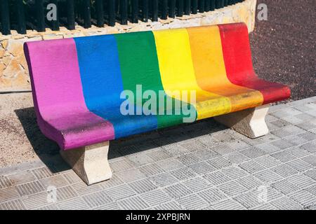 Banc avec les couleurs de l'arc-en-ciel peint dessus. Siège en bois peint dans des couleurs arc-en-ciel, ajoutant une touche joyeuse à l'environnement et favorisant dans Banque D'Images