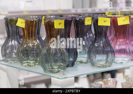 Des vases en verre coloré sont vendus en magasin. Bocaux pour fleurs. Banque D'Images