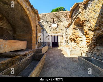 Bâtiment funéraire d'un ou deux étages carrés, souvent entouré d'un enclos ; plafonds voûtés en tonneau ou toits plats ; façades composées de briques ornées de pignons triangulaires, de socles, de lesènes, de colonnes et de chapiteaux ; petites fenêtres et portes encadrées de seuils en travertin, de montants et d'épistyles. La nécropole s'est développée sur les côtés de la via Flavia entre la fin des Ier et IVe siècles après JC - nécropole de Portus dans l'Isola Sacra, Fiumicino, Rome, Italie Banque D'Images