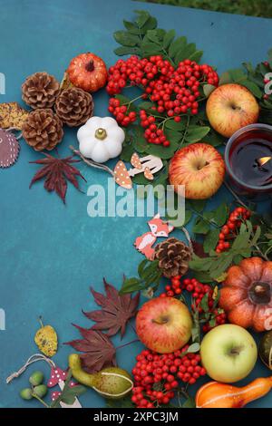 Pommes, citrouilles, cônes, feuilles, baies de rowan sur une table. Photo vue de dessus de la composition d'automne. Concept de saison de récolte. Banque D'Images