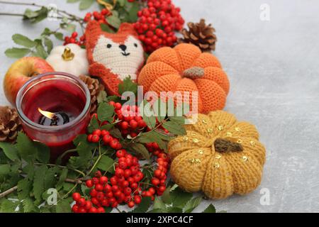 Jouet renard fait à la main, citrouilles, pommes, baies de rowan et une bougie sur un fond clair avec un espace pour le texte. Photos rapprochées des décorations d'automne. Banque D'Images