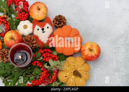 Jouet renard fait à la main, citrouilles, pommes, baies de rowan et une bougie sur un fond clair avec un espace pour le texte. Photos rapprochées des décorations d'automne. Banque D'Images