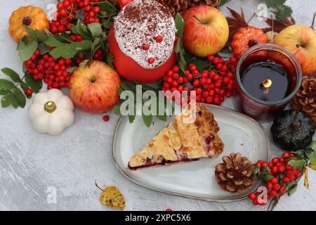 Nature morte d'automne avec une tasse de café chaud, tarte aux myrtilles, bougie, citrouilles et baies de rowan. Tarte sucrée de saison maison sur une table. Banque D'Images