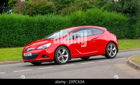 Whittlebury, Norhants, Royaume-Uni - 4 août 2024. 2013 voiture rouge Vauxhall Astra conduisant sur une route de campagne britannique Banque D'Images