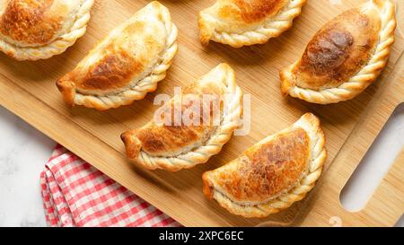 Empanadas de bœuf argentin sur une planche de bois sur fond de marbre et une serviette rouge et blanche. Banque D'Images