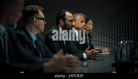 Homme du moyen-Orient Chef de délégation politique s'exprimant lors de la conférence de presse du Forum économique international. Politicien de haut niveau qui rend compte des accords réussis. Différents participants écoutent. Banque D'Images