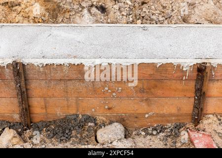 Béton fraîchement posé, mur de fondation en coffrage en bois. La maison rurale est en construction Banque D'Images