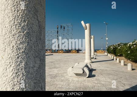 Les ouvriers démantèlent les échafaudages de scène après un événement musical organisé sur la plage près de la Piazza Primo Maggio à Pescara, en Italie. Banque D'Images