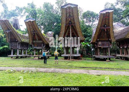 Mère et fils, touristes explorant des greniers à riz à Buntu Pune, village traditionnel Torajan avec des toits couverts de végétation, Sulawesi, Indonésie Banque D'Images