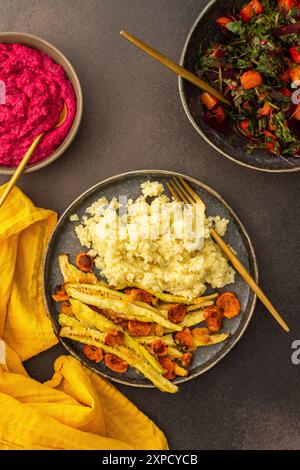 Profitez d'un copieux petit déjeuner ou déjeuner avec millet, courgettes cuites au four et carottes, accompagné d'une salade fraîche de légumes et d'herbes de saison, de petits pains aux pois chiches, Banque D'Images