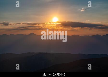 Le soleil couchant sur les montagnes, les beaux rayons du soleil brillent à travers les nuages, le fond naturel, la liberté, la tranquillité et la paix Banque D'Images