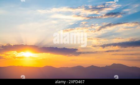 Le soleil couchant sur les montagnes, les beaux rayons du soleil brillent à travers les nuages, le fond naturel, la liberté, la tranquillité et la paix Banque D'Images