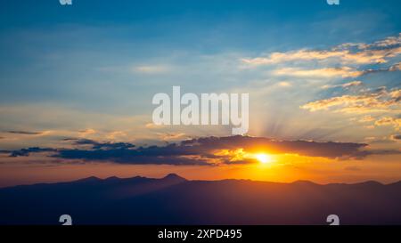 Le soleil couchant sur les montagnes, les beaux rayons du soleil brillent à travers les nuages, le fond naturel, la liberté, la tranquillité et la paix Banque D'Images