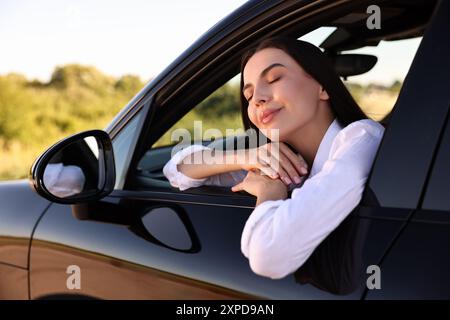 Belle jeune femme penchée par la fenêtre de la voiture, vue de l'extérieur. J'apprécie le voyage Banque D'Images