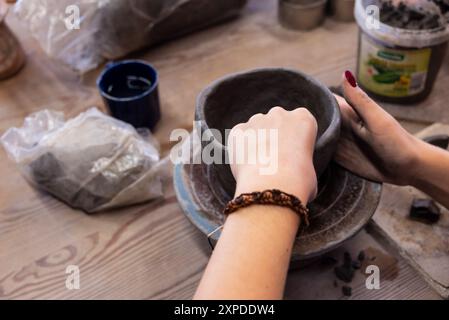 mains féminines sculptant un pot dans de l'argile pendant un cours de poterie Banque D'Images