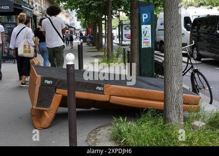 Paris, France - 07 juin 2024 : canapé en cuir jeté dans la rue. Les gens qui marchent sur le trottoir Banque D'Images