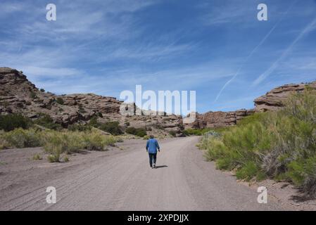 Senior féminine, portant un Jean et une chemise en denim, marche le long du chemin de terre menant au canyon de San Lorenzo au Nouveau-Mexique. Banque D'Images