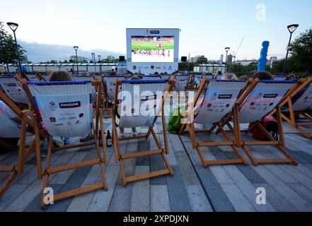 Les spectateurs regardent une projection de l'athlétisme pendant les Jeux Olympiques de Paris 2024 dans la zone officielle Team GB Fan, à Power Station Park, Battersea Power Station, Londres. Date de la photo : lundi 5 août 2024. Banque D'Images