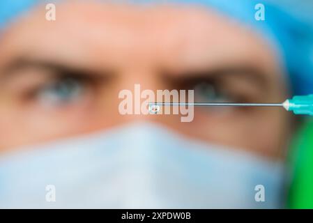 Vaccination et immunisation en milieu hospitalier. Docteur en masque médical avec seringue se préparant à l'injection. Gros plan de l'aiguille. Mise au point sélective. Professionnel m Banque D'Images