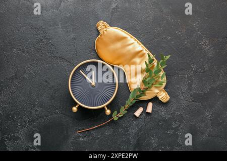 Bouchons d'oreilles avec masque de sommeil et réveil sur fond sombre Banque D'Images