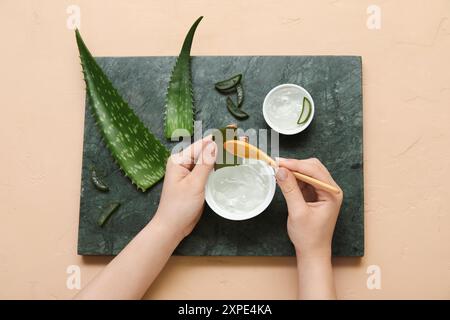 Femme faisant du gel d'aloe vera sur fond beige Banque D'Images