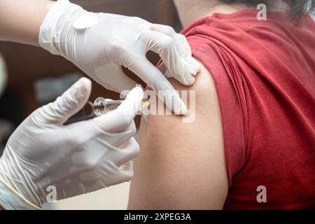 Une femme se fait tirer dans le bras. L'infirmière porte des gants et tient une seringue Banque D'Images