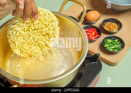 Une personne fait cuire des nouilles instantanées dans une casserole. Les nouilles sont bouillies dans une casserole avec de l'eau Banque D'Images