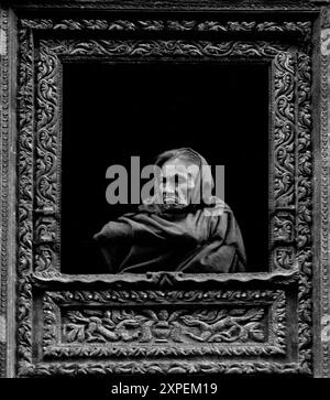 Une grand-mère regarde sa fenêtre en bois sculptée à la main à Bhaktapur - Népal 1989 Banque D'Images