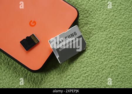 Terengganu, Malaisie - 23 août 2024 : gros plan de l'adaptateur sd samsung et de la carte microsd noire sur google pixel 4 sur fond vert. Banque D'Images