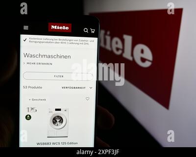 Personne tenant le téléphone portable avec la page Web de la société allemande d'appareils ménagers Miele Cie. KG devant le logo. Concentrez-vous sur le centre de l'écran du téléphone. Banque D'Images
