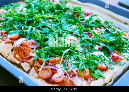 Pizza maison avec rucola, tomates fraîches et oignons rouges Banque D'Images